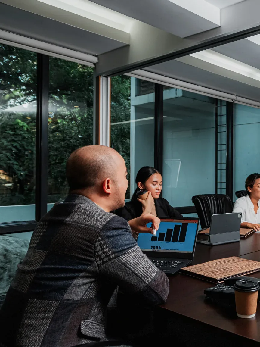 Participantes de uma reunião ao redor da mesa com notebooks